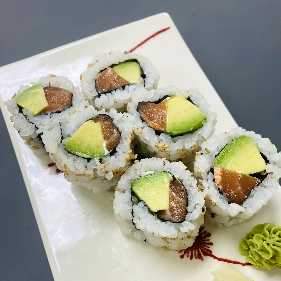 Alaska roll pieces with salmon and avocado on a white plate with pickled ginger and wasabi at Hana Sushi, Winnipeg