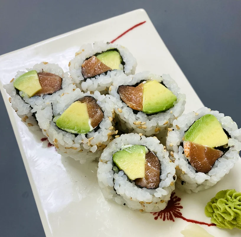 Alaska roll pieces with salmon and avocado on a white plate with pickled ginger and wasabi at Hana Sushi, Winnipeg